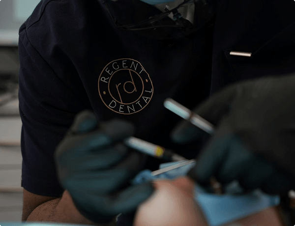 Close-up of Dr Naeem Ashfaq treating a patient in Regent Dental scrubs
